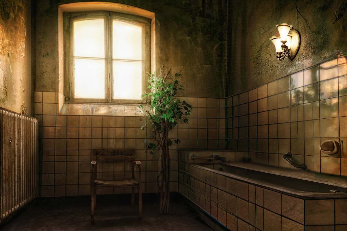 moody candlelit bath with brass taps and dried herbs hung above the door
